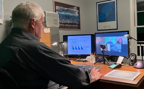 A man sitting at his desk with two computers.